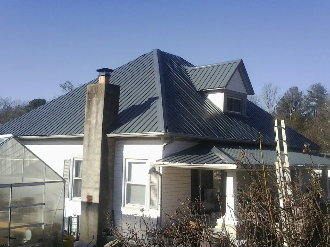 Dark blue standing seam metal roof on a white farmhouse with dormer — Slate & Tile Roof Repair by Roofing Brothers in Cropseyville