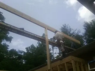 Carpenter setting a ridge beam over a new addition frame — Ice Dam Removal by Roofing Brothers in Cropseyville