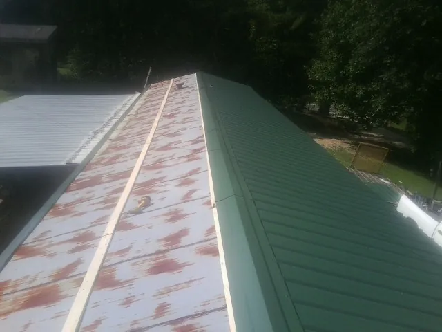 Old rusted panels beside newly installed green metal roofing — Wind Damage Roof Repair by Roofing Brothers in Cropseyville