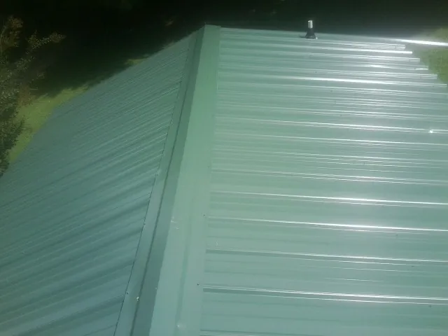 New green metal panels meeting at the ridge of a roof — Flat Roof Repair work by our crew in Cropseyville