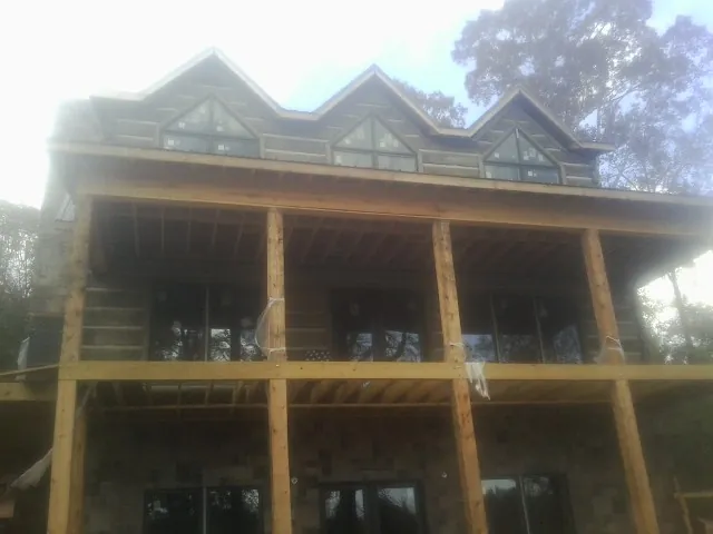 Dormers and porch framing on a large log home under construction — Roof Coating work by our crew in Cropseyville