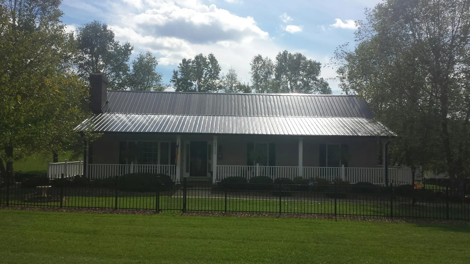 Gray metal roof on a brick ranch with a full width front porch — Gutter Guard Installation work by our crew in Cropseyville