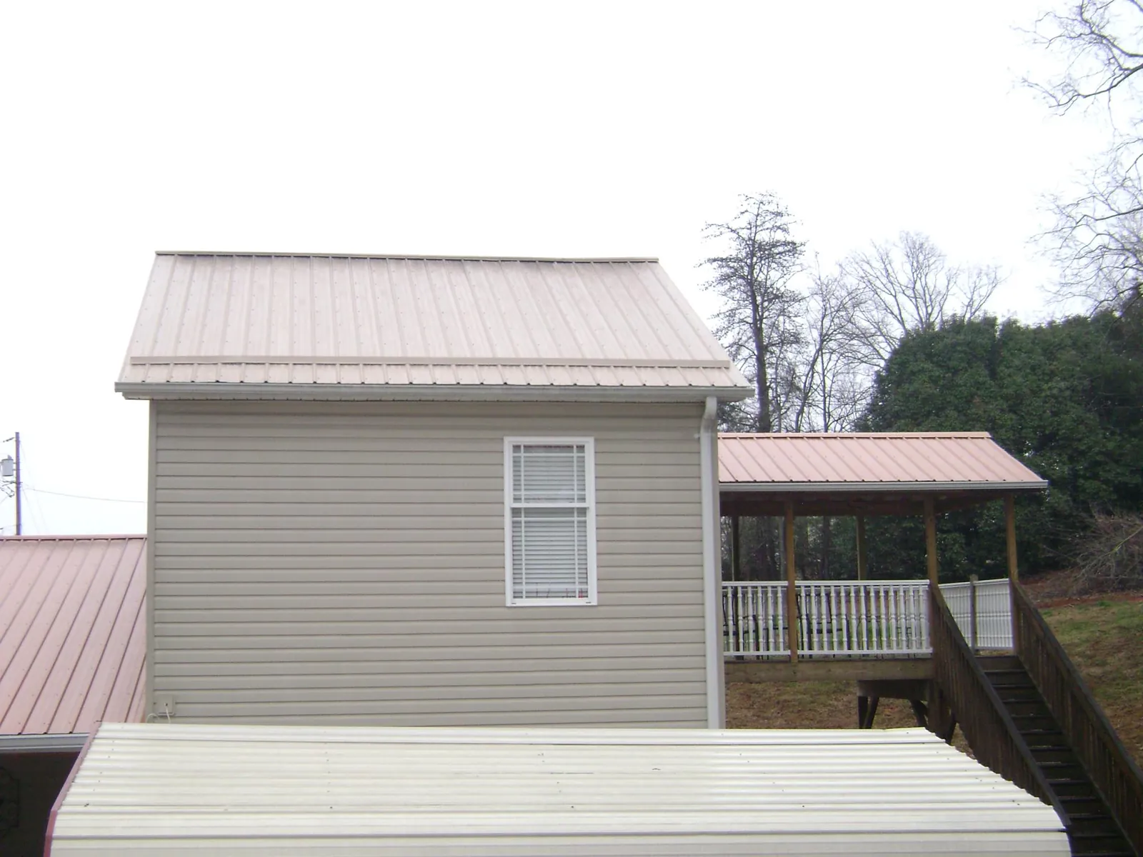 Tan metal roofs on a two story addition and attached porch, from a Roof Replacement job in Cropseyville