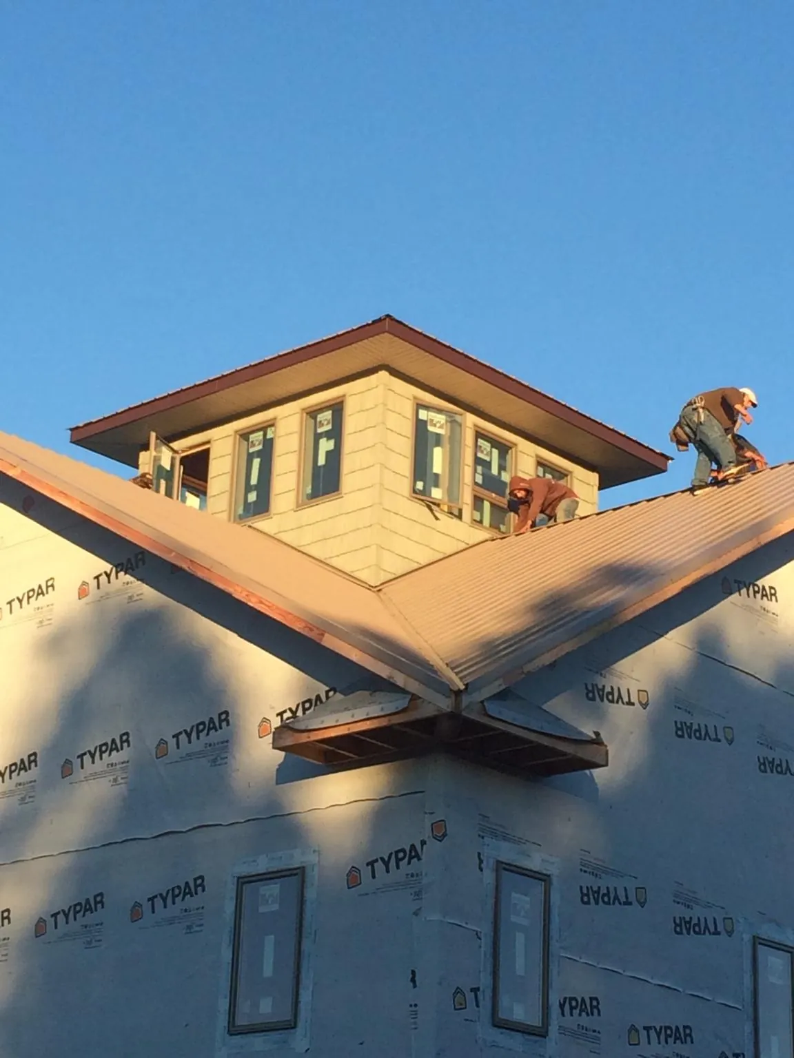 Roofers working around a rooftop cupola on a new metal roof at sunset — Roof Waterproofing in Cropseyville by Roofing Brothers